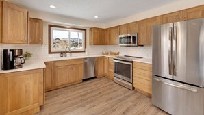 A modern kitchen with wooden cabinets, stainless steel appliances, and a window providing a view of the outside. - Downtown Modern Frisco Getaway (Frisco)