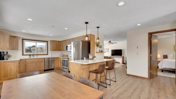 A modern kitchen with wooden cabinets, stainless steel appliances, and a central island with bar stools. - Downtown Modern Frisco Getaway (Frisco)