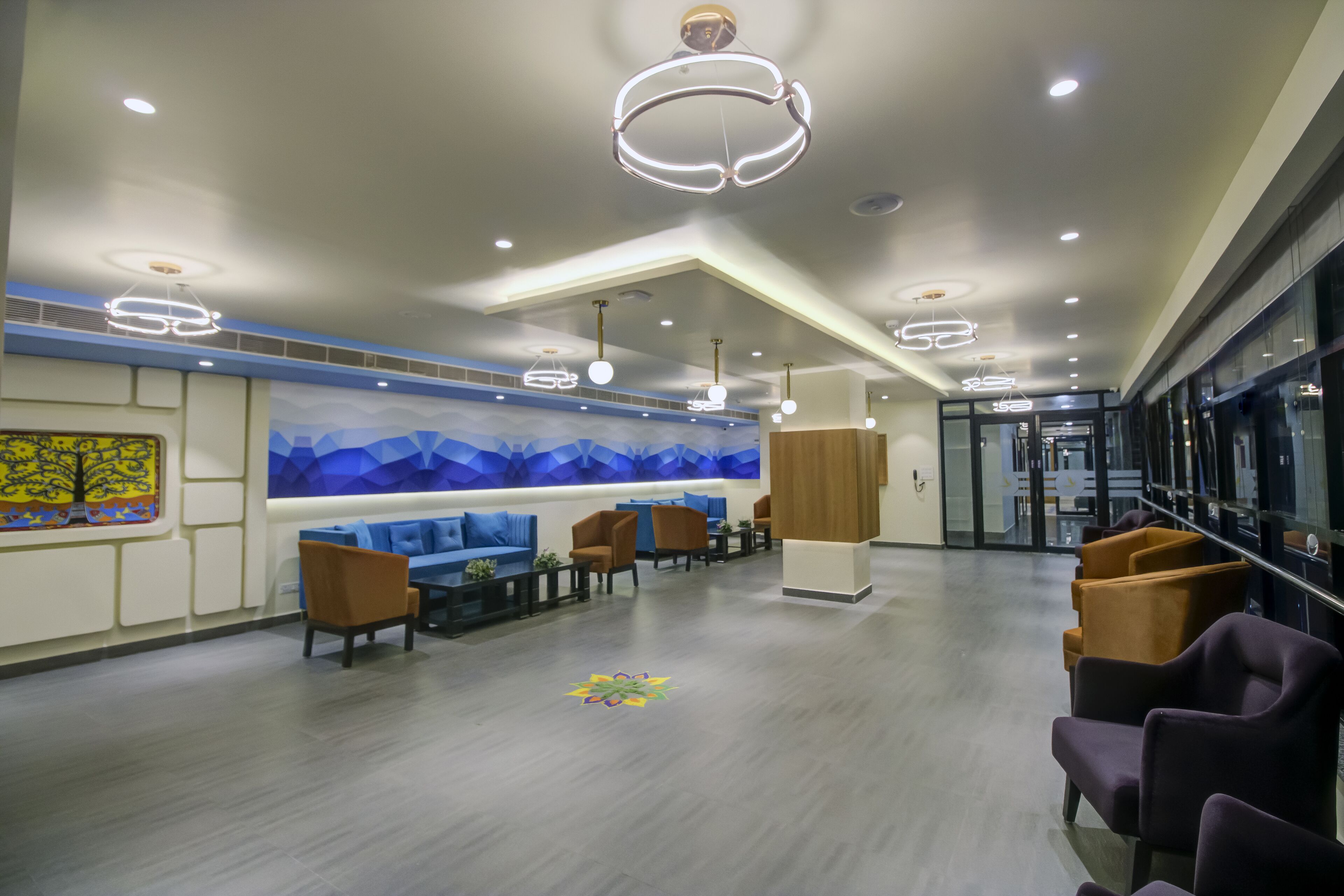 A modern lobby with a seating area, a reception desk, and a mural on the wall.