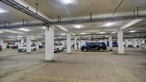 An indoor parking garage with multiple levels, concrete pillars, and a tiled floor. - The Bindal Hotel (Jamshedpur)