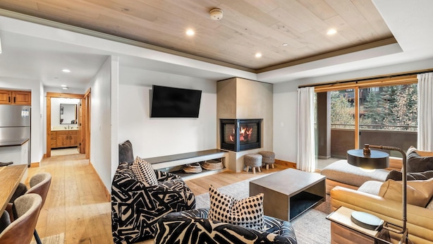 Una sala de estar moderna con chimenea, televisor de pantalla plana y comedor con piso de madera.