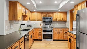 Una cocina moderna con armarios de madera, electrodomésticos de acero inoxidable y una encimera negra.