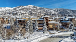 Un pueblo nevado en la montaña, con edificios y una pista de esquí al fondo.