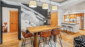 Una cocina moderna con armarios de madera, un refrigerador de acero inoxidable y una barra con taburetes.
