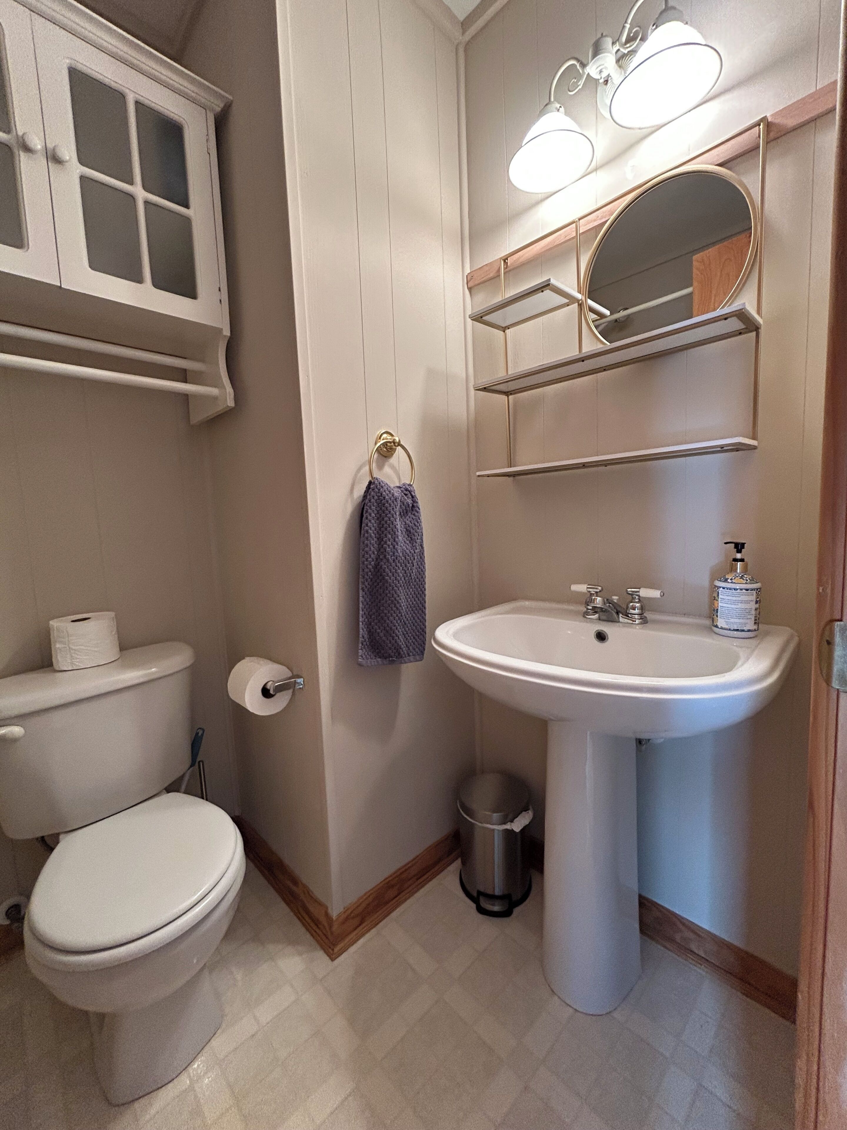 A bathroom with a toilet, sink, and mirror.