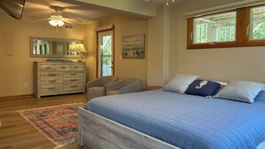 A bedroom with a bed, a dresser, a chair, a ceiling fan, and a window. - Spacious 3BR/3BA Beach House on Quiet Wooded Lot – Minutes from the Ocean (Kitty Hawk)