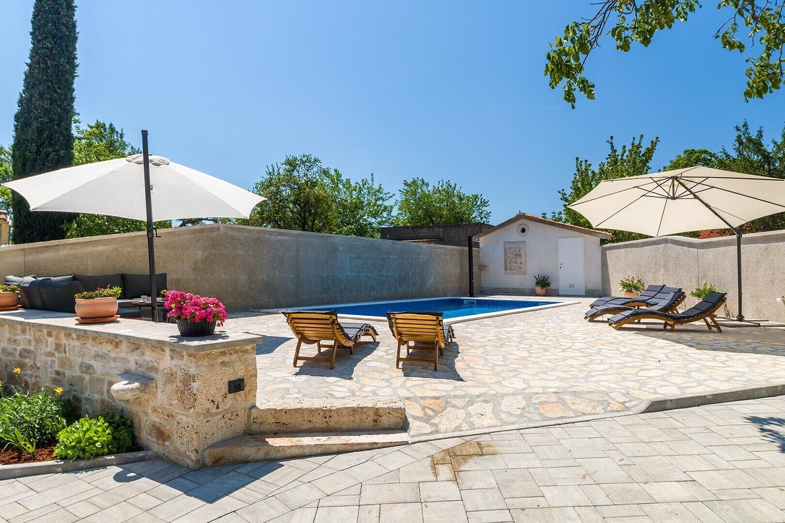 A poolside area with lounge chairs, a small pool, and umbrellas.