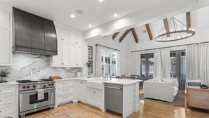 A spacious kitchen with white cabinetry, a marble backsplash, and a built-in oven.
