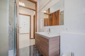A modern bathroom with a vanity, a sink, a mirror, and a shower.