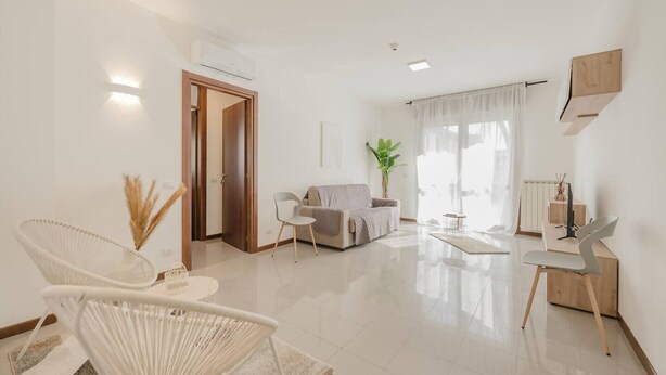 A spacious living room with a sofa, two chairs, a coffee table, and a dining area with a table and chairs. - Unico Apt 4, Free Parking, 6 guests, for families (Mestre)