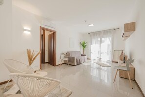 Un salón amplio con un sofá, dos sillones, una mesa de centro y una zona de comedor con una mesa y sillas.