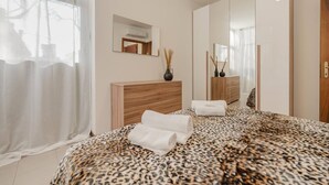A modern bedroom with a large bed, a wooden dresser, a mirror, and a window with sheer curtains. - Unico Apt 4, Free Parking, 6 guests, for families (Mestre)
