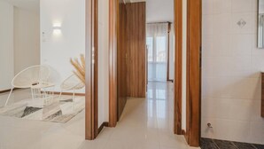 A modern interior with a wooden door leading to a hallway, a white chair, and a patterned rug. - Unico Apt 4, Free Parking, 6 guests, for families (Mestre)