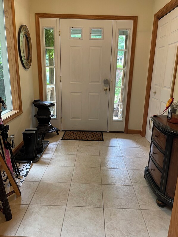 A hallway with a double door, a doormat, a small black stove, and a wooden cabinet.