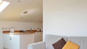 A modern kitchen with white cabinets and a wooden countertop. - Stable Barn Apartment at Bodmin Moor (St Breward)