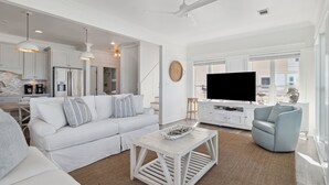 A spacious living area with a white sofa, a coffee table, and a television. - Gulf Views with Hot Tub, Garage and Bikes (Santa Rosa Beach)
