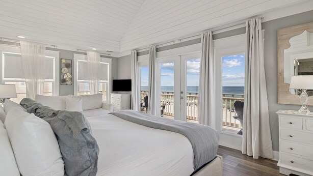 A spacious bedroom with a large bed, a television, and a balcony with a view of the beach. - Gulf Views with Hot Tub, Garage and Bikes (Santa Rosa Beach)