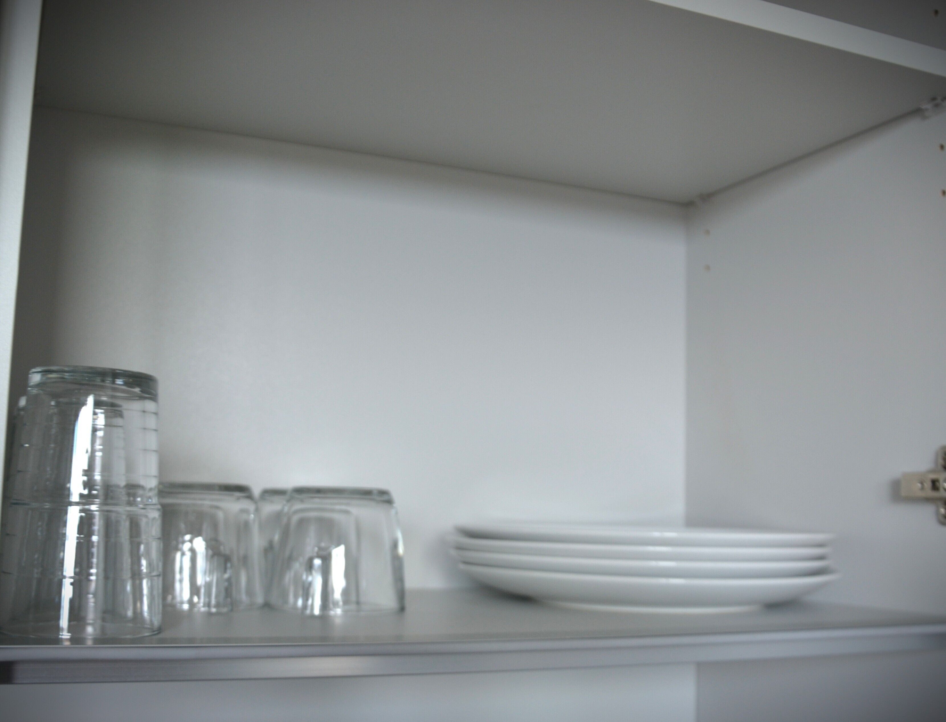 A kitchen counter with a stack of white plates and a row of clear glass jars.