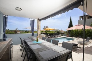 An outdoor patio with a dining table, chairs, and a pool area. - 5-bedroom Villa Eminentia with Sea View and Private Pool (Ližnjan)
