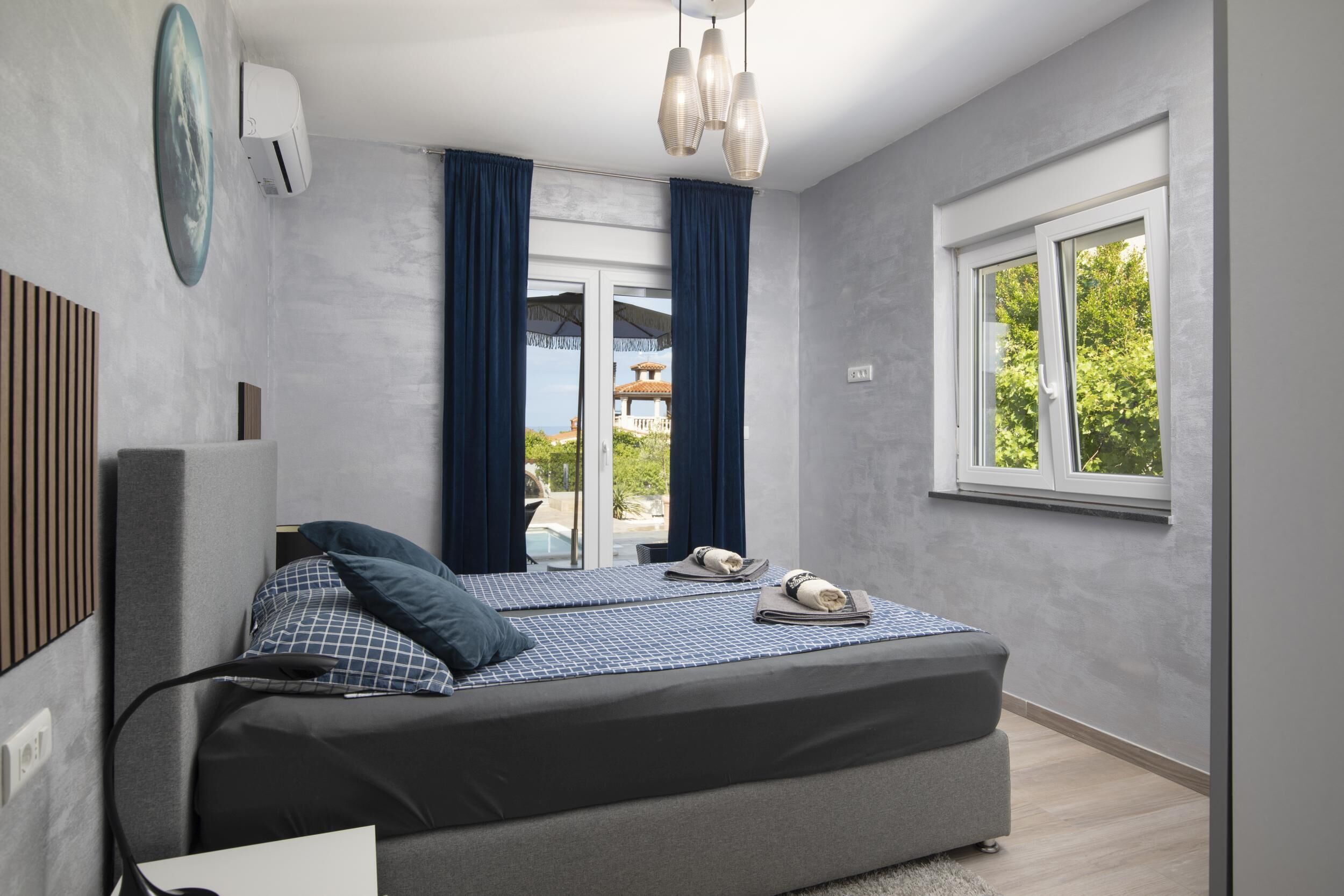 A modern bedroom with a large bed, two bedside tables, a desk, and a window with curtains.