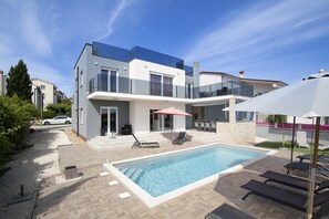 A modern two-story house with a swimming pool, outdoor seating, and a car parked nearby. - 5-bedroom Villa Eminentia with Sea View and Private Pool (Ližnjan)