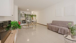 Un soggiorno moderno con un divano, una TV e un'area pranzo con tavolo e sedie.