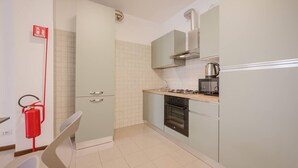 Una cucina compatta con fornello a gas, forno e macchina da caffè sul piano di lavoro.