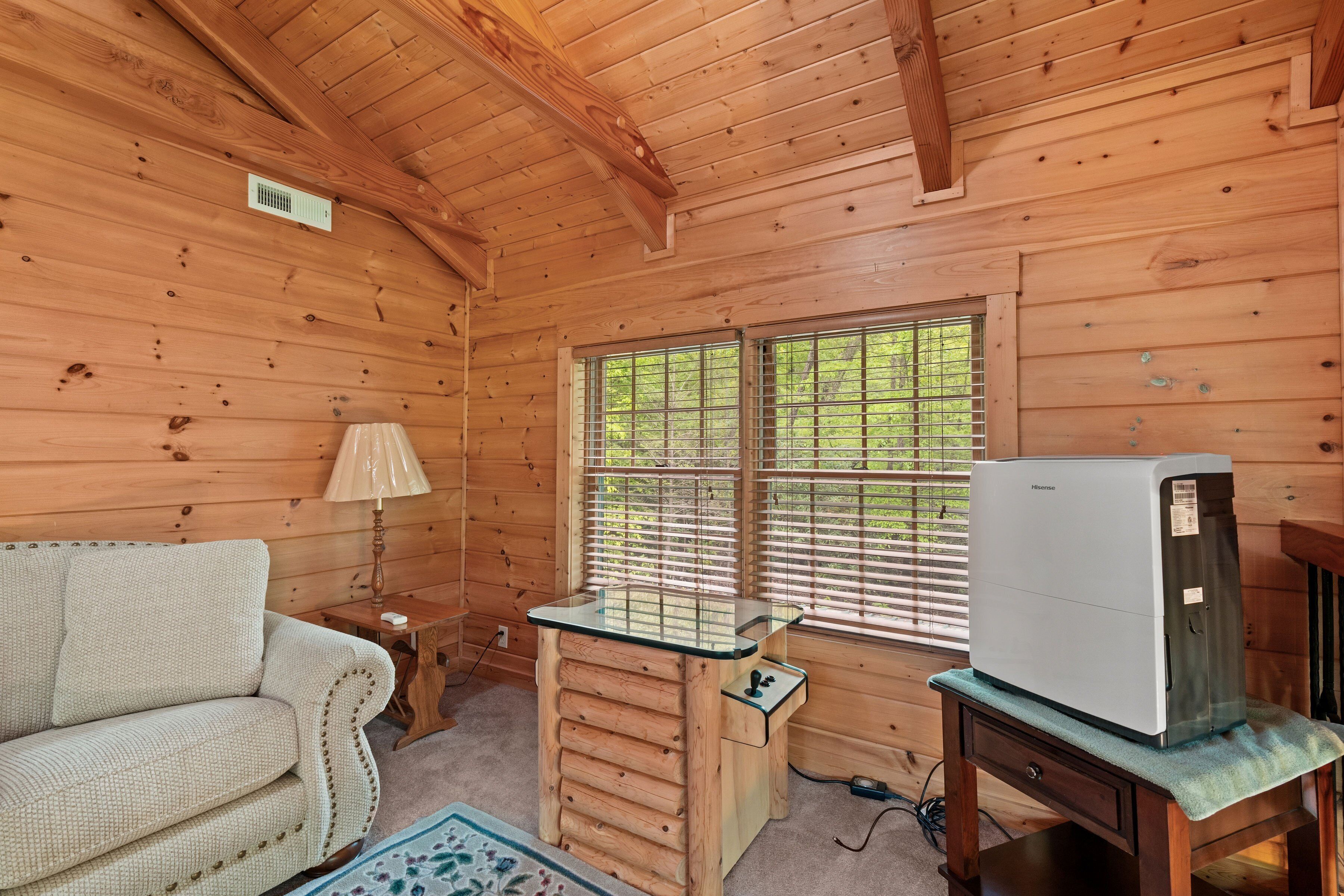 Een houten cabin met een bank, een tafel met een lamp en een koelkast.