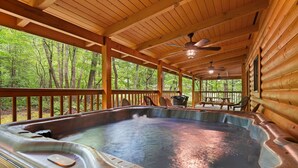 A hot tub in a wooden cabin with a view of a forest. - Elk Rapids On Cosby Creek 3 Bedroom Cabin (Cosby)