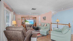 A living room with a sofa set, a television, and a wooden floor.