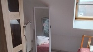 Une chambre à coucher avec un lit, une armoire, un miroir et une fenêtre.