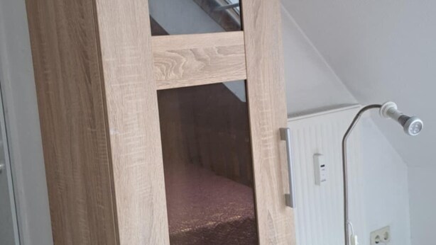 Un grand meuble en bois, doté d’une porte en verre et d’une étagère inférieure.