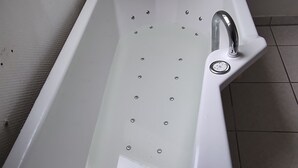Une salle de bain moderne avec une baignoire sur pieds, une douche intégrée et un sol carrelé.