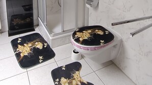 Une salle de bain dotée d’une douche à parois de verre, de toilettes avec un abattant noir et d’un bidet.