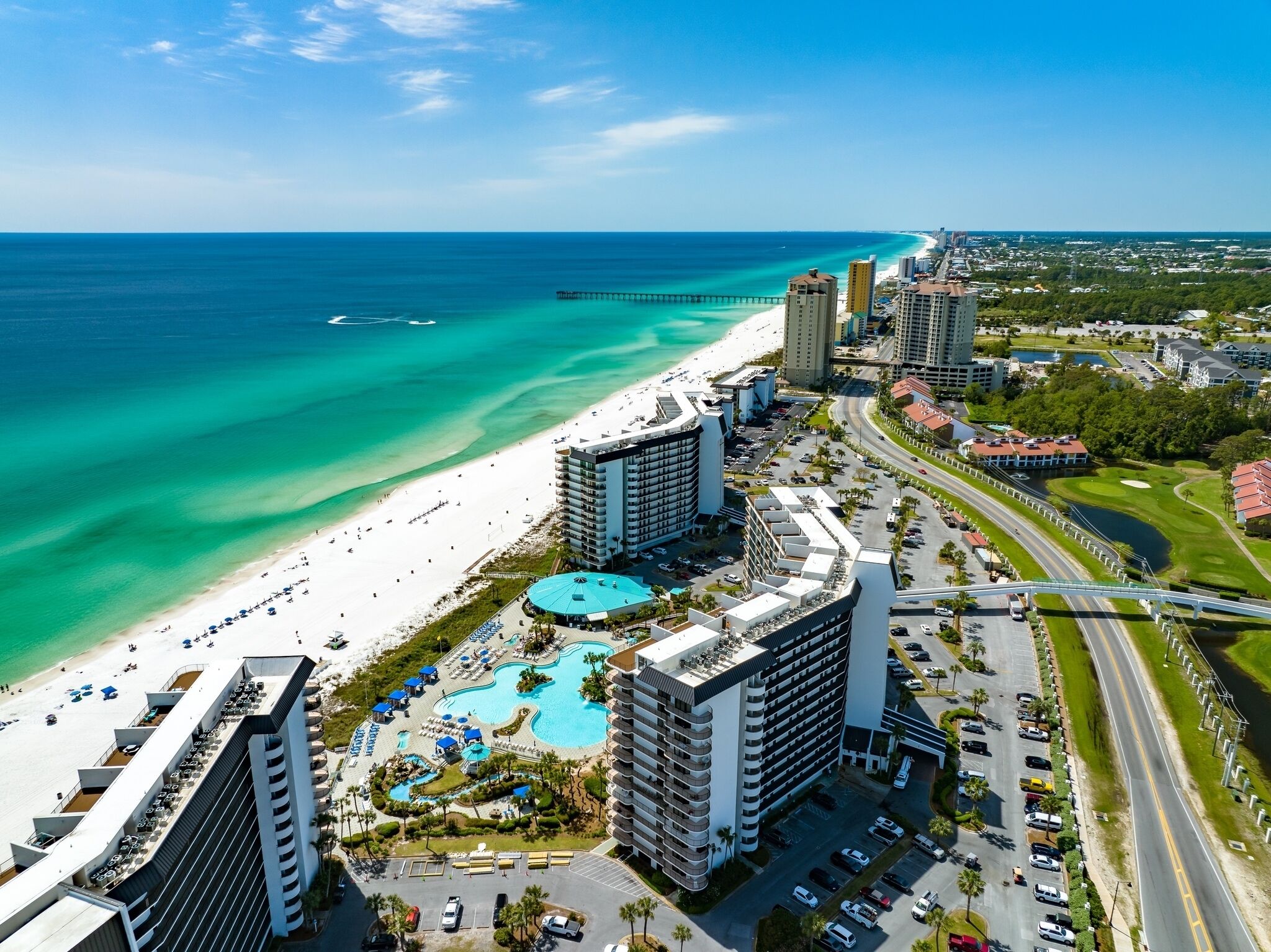 A coastal hotel with a large pool, beachfront, and high-rise buildings.