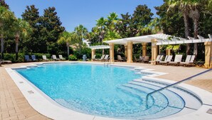 Ein rechteckiger Swimmingpool mit klarem, blauem Wasser, umgeben von Liegestühlen und Palmen.
