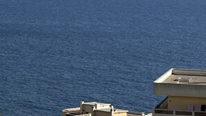 Une vue sur la côte, avec un ciel dégagé, une mer calme et une terre lointaine à l’horizon.