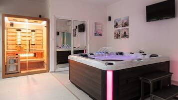 Une salle de bain moderne avec un grand jacuzzi, un sauna en bois et un miroir.