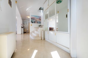 Un couloir moderne avec un escalier, une vue sur un paysage lointain et un coin cuisine.
