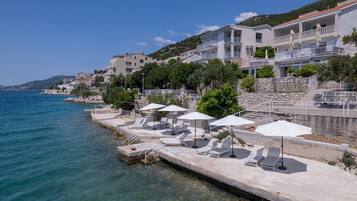Un hôtel situé sur la côte, doté d’un espace piscine, de chaises longues et de parasols.