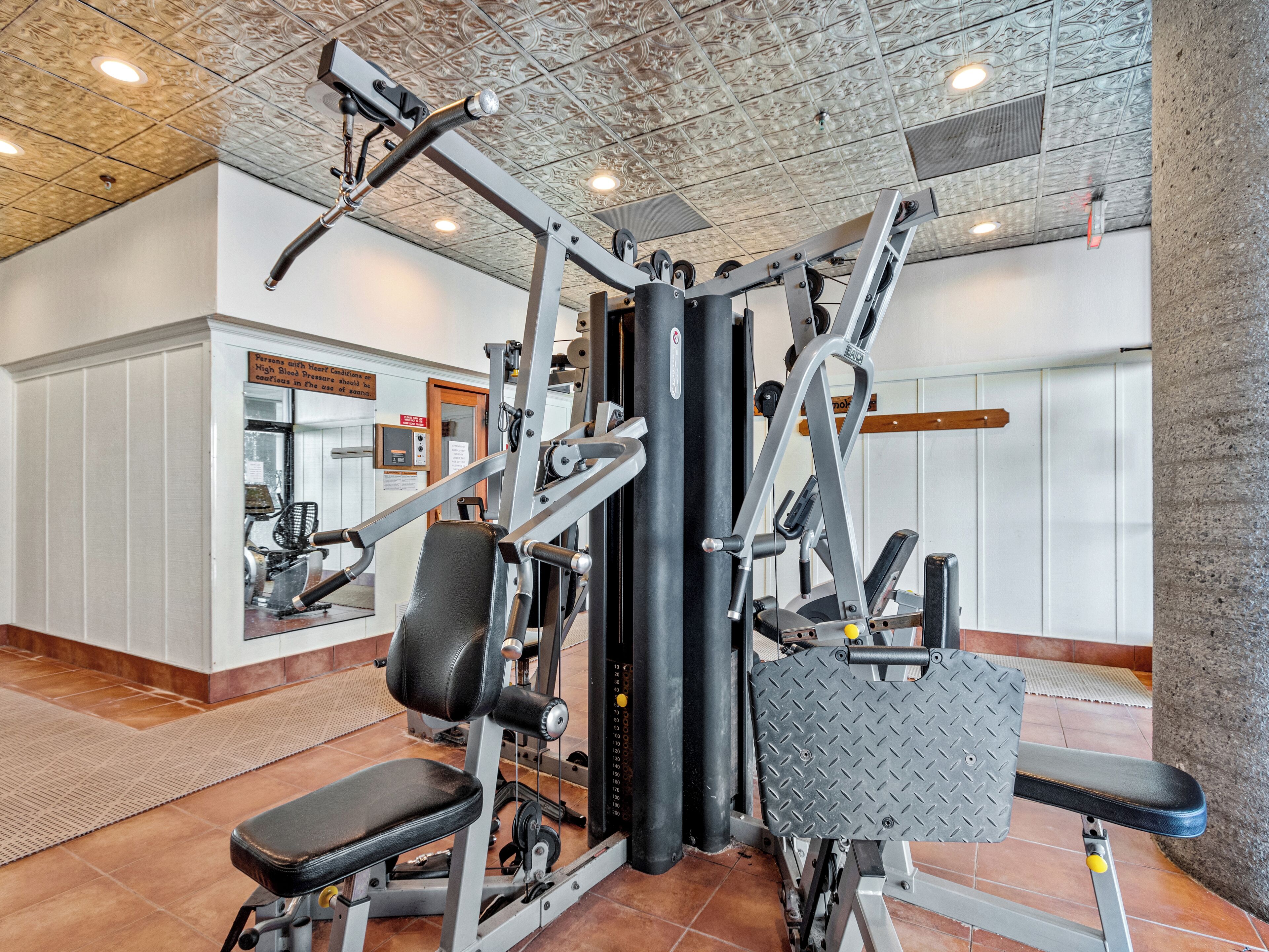 Una palestra con diverse macchine per esercizi, uno specchio a parete e un soffitto con decorazioni.