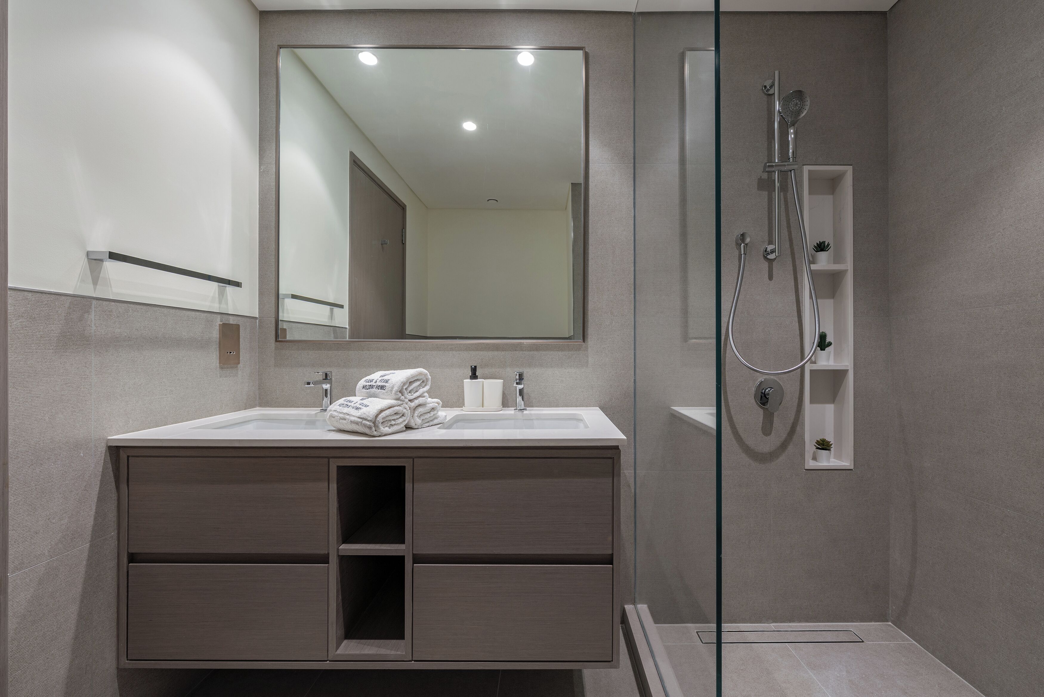 A modern bathroom with a large mirror, a sink with a towel rack, and a shower area.