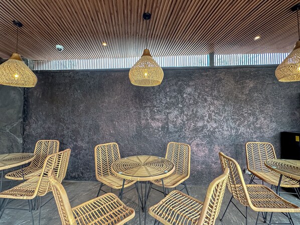 A modern interior with wicker furniture, a dark textured wall, and wooden slatted ceiling.