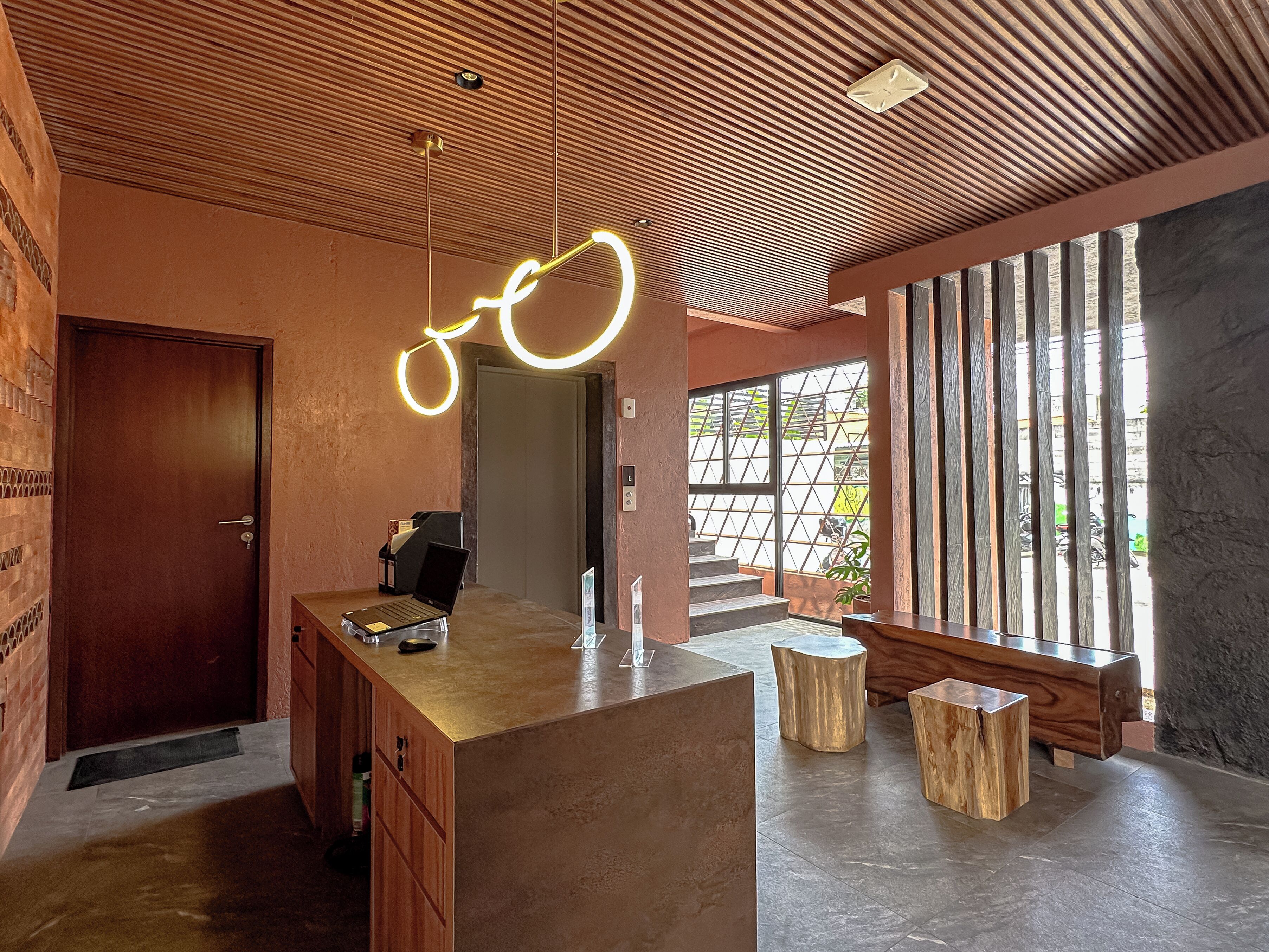 Un interior moderno con mostrador de recepción, detalles de madera y ventanas amplias que dejan entrar la luz natural.