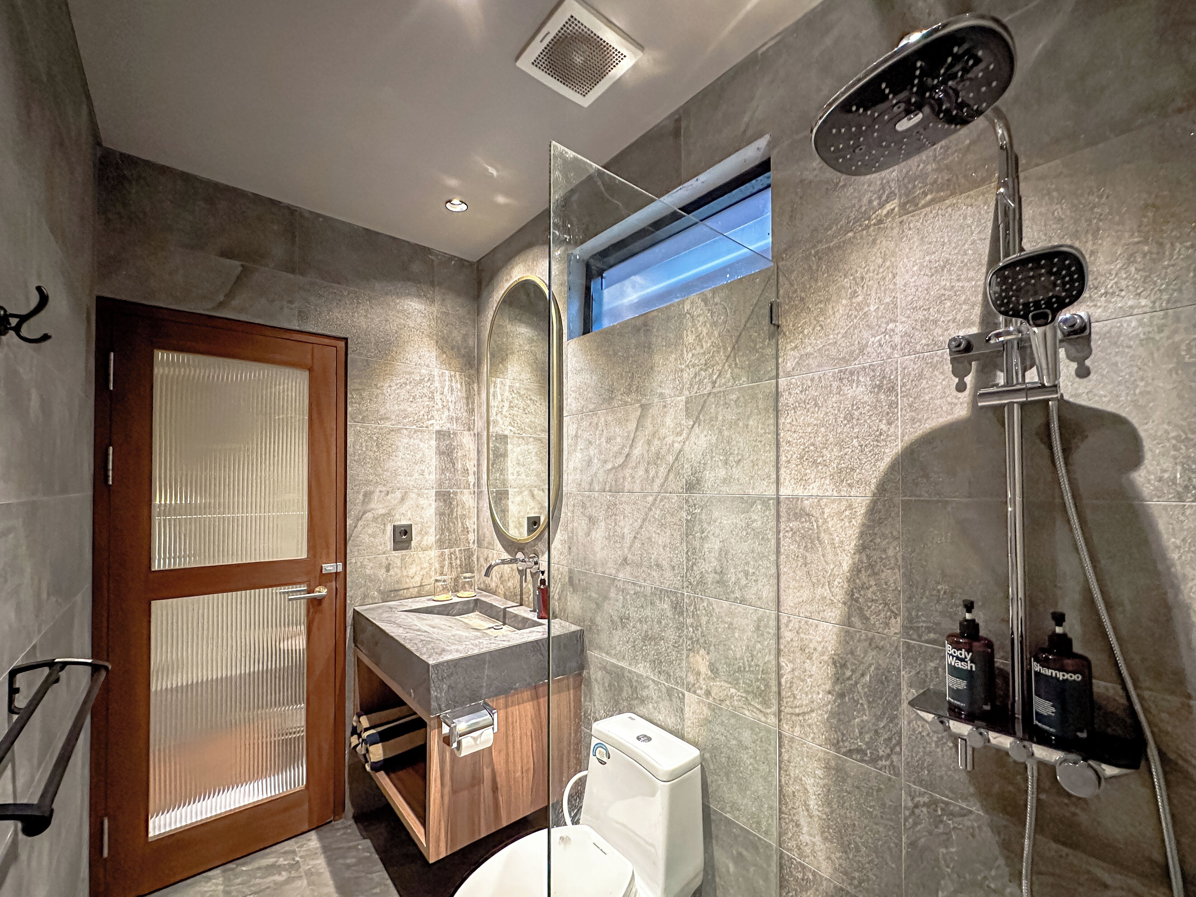 Un baño moderno con ducha de vidrio, tocador de madera y un inodoro.
