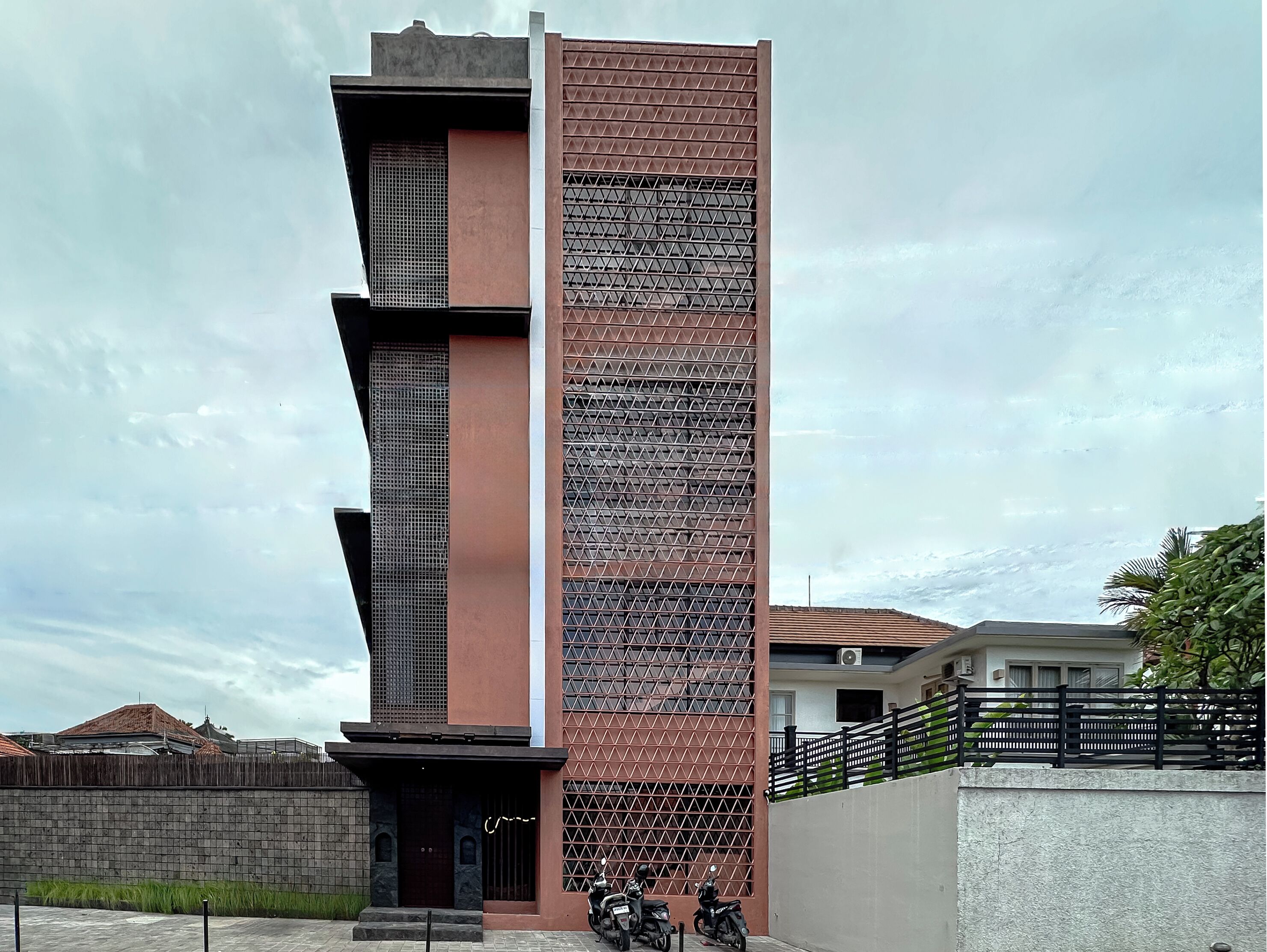 A modern building with a vertical design, featuring a mix of brick and metal panels.