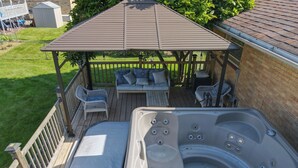 Ein Whirlpool mit Baldachin, eine Terrasse mit Gartenmöbeln und ein eingezäunter Garten.