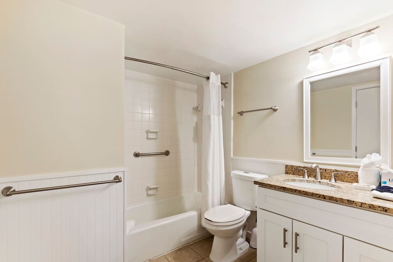 Un baño con bañera, inodoro y tocador con espejo.