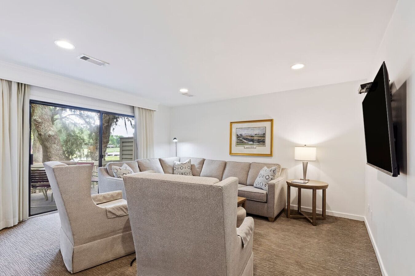 A modern living room with a sofa set, a small table, and a TV mounted on the wall.