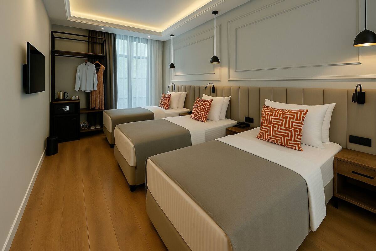 A hotel room with three beds, a wardrobe, and a TV.